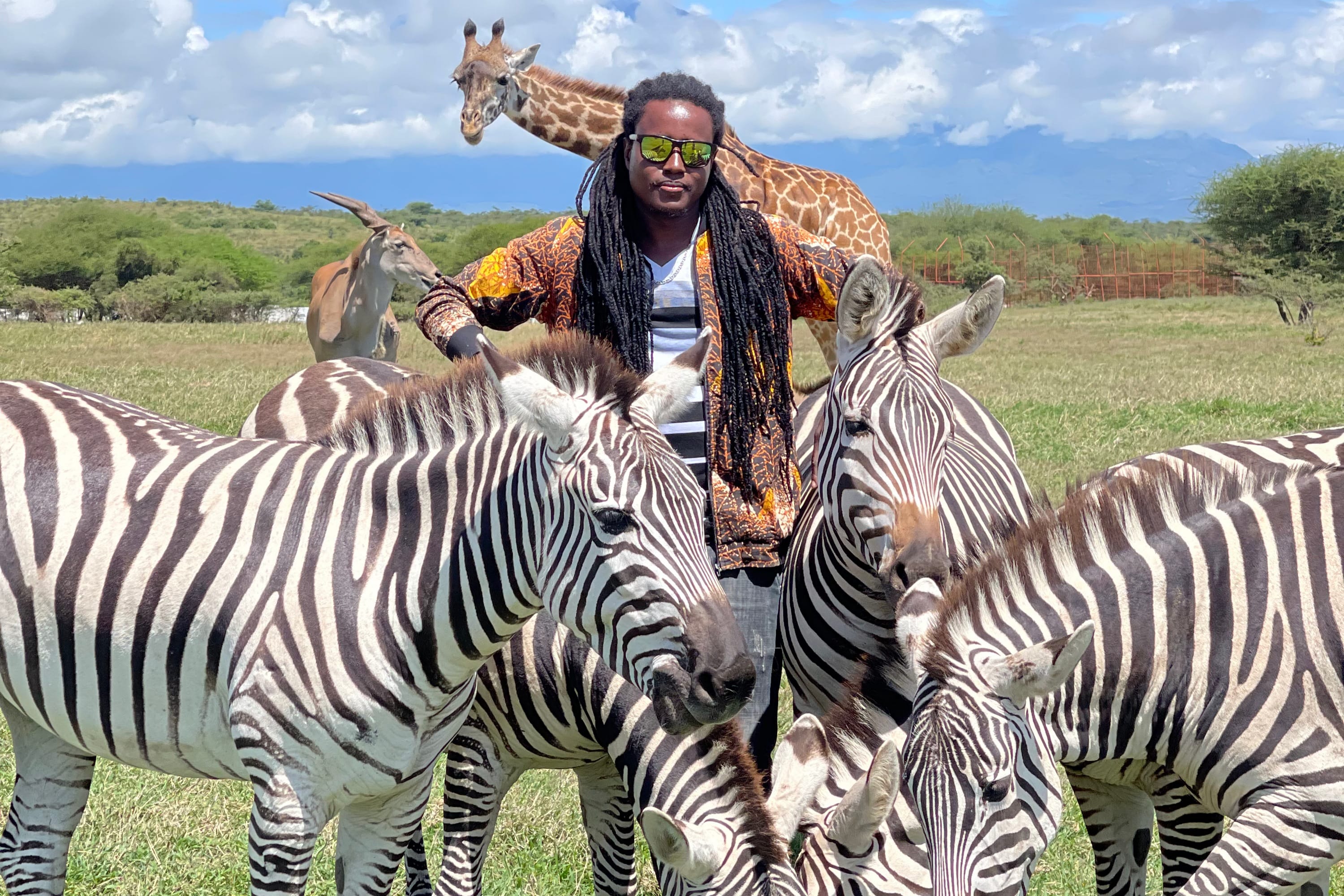 A guide surrounded by zebras with giraffes in the background at a private conservation park.