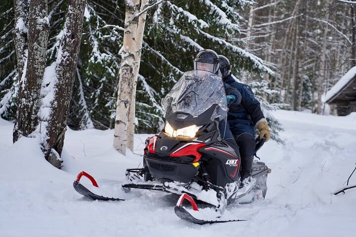 Snowmobile riding through the forest in Rovaniemi with StayLapland.