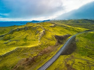 An aerial view of a long and winding road, threading its way through mountainous landscapes