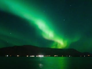 Beautiful Northern Lights glowing across the Icelandic night sky during a scenic boat tour from Reykjavík Harbour.