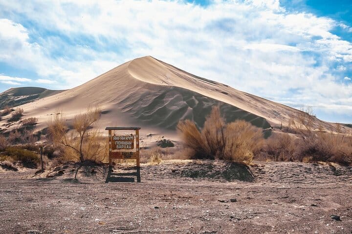Sand dune rising above rocky desert valleys in Altyn-Emel National Park.