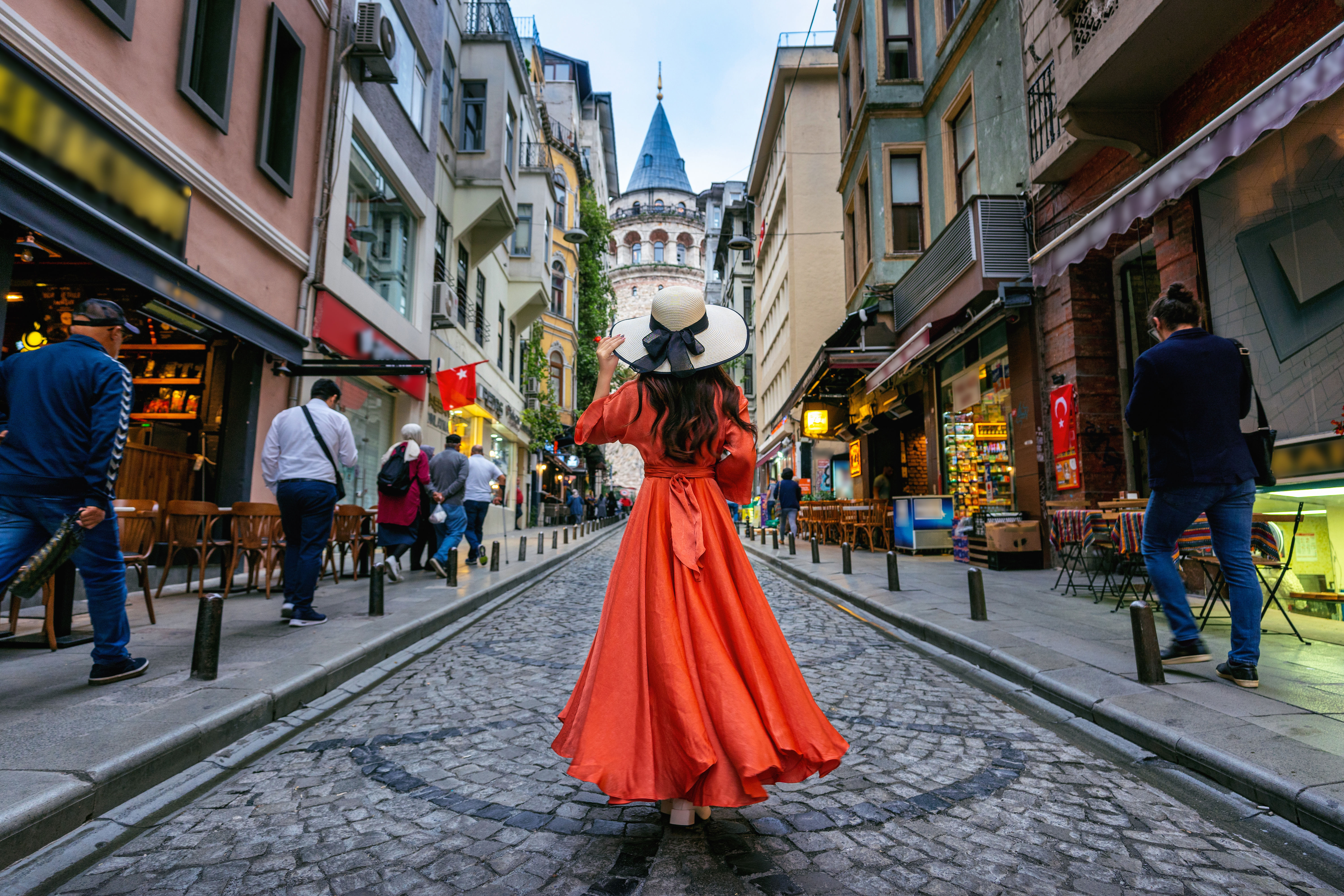 “View of the historic Galata Tower overlooking crowded İstiklal Street filled with people, shops, and cafes in Istanbul.”
