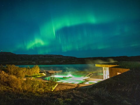The Northern lights dancing over the geothermal pools at Vök baths.