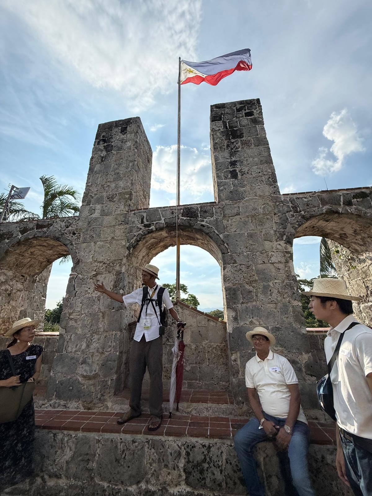 a Cebu cultural guide shares Cebu’s history with travellers beneath the Philippine flag at Fort San Pedro.