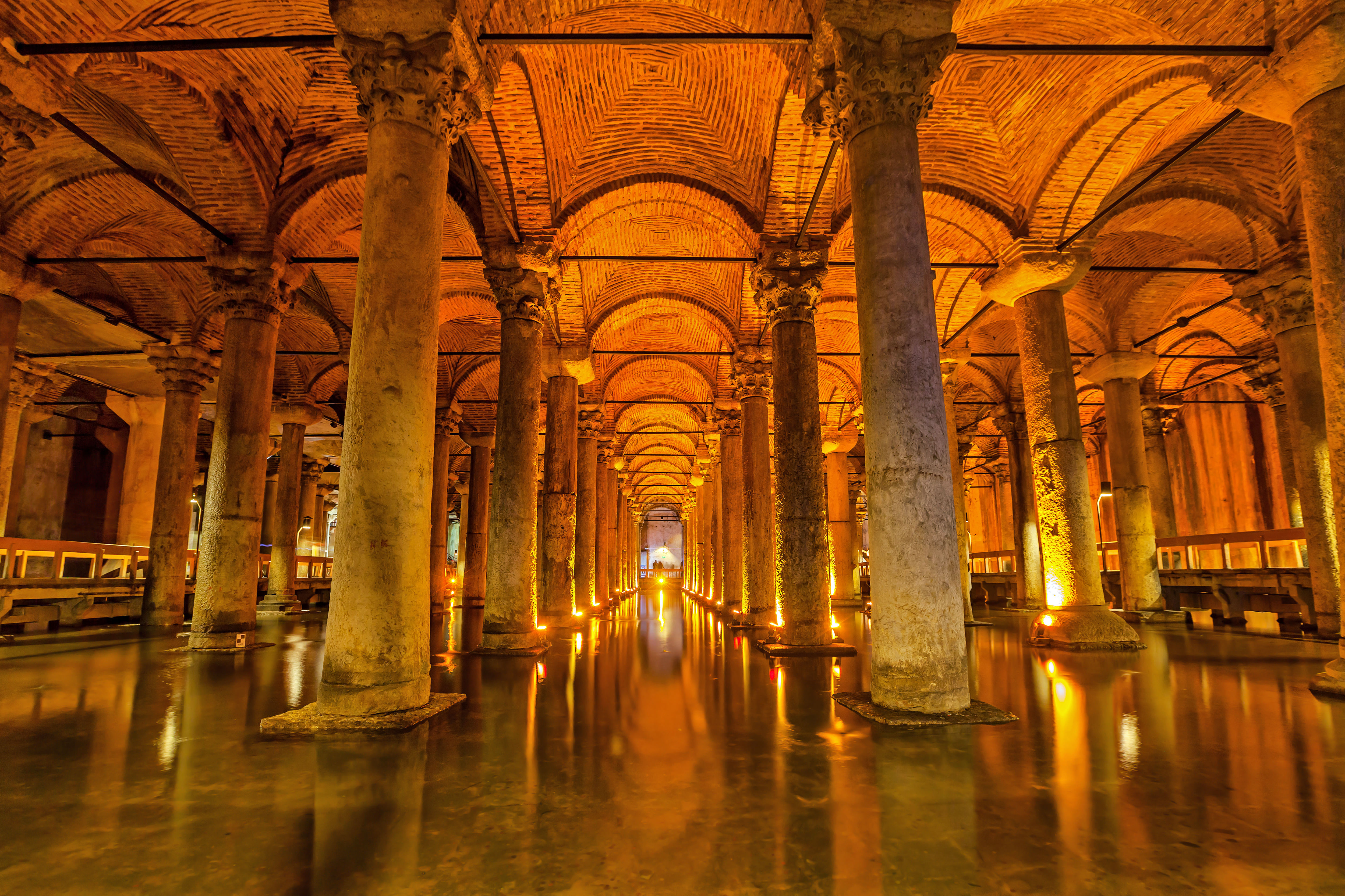“Interior of Istanbul’s Basilica Cistern showing rows of tall stone columns standing in shallow water, with dim lighting creating a mysterio