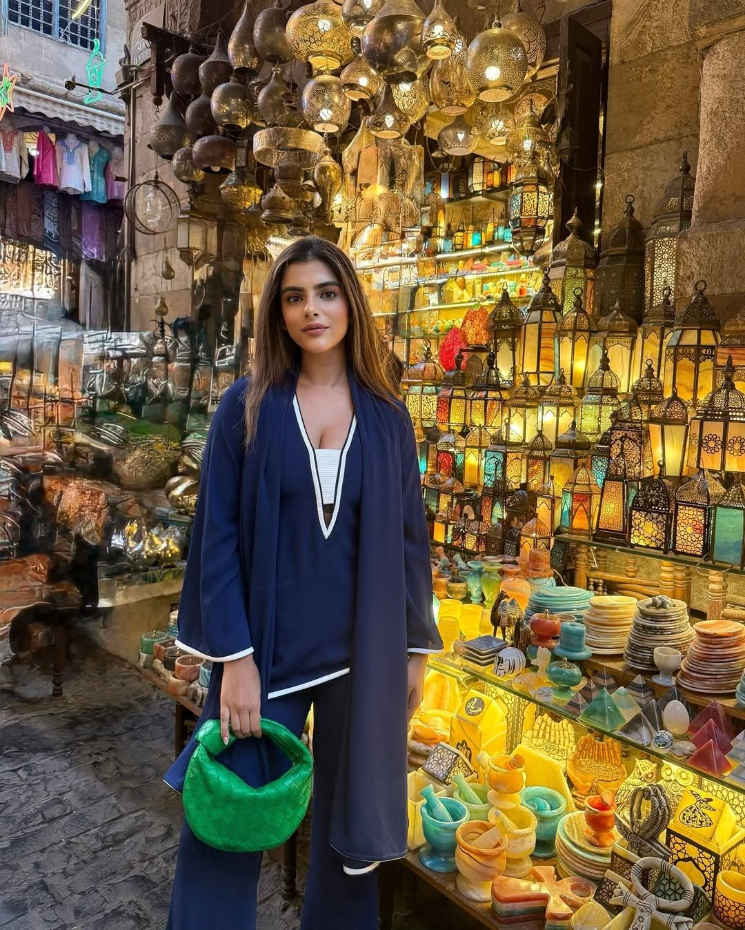 Tourists walking through the colorful bazaar stalls, browsing gold jewelry, spices, and handmade crafts, while sipping mint tea in Cairo’s h