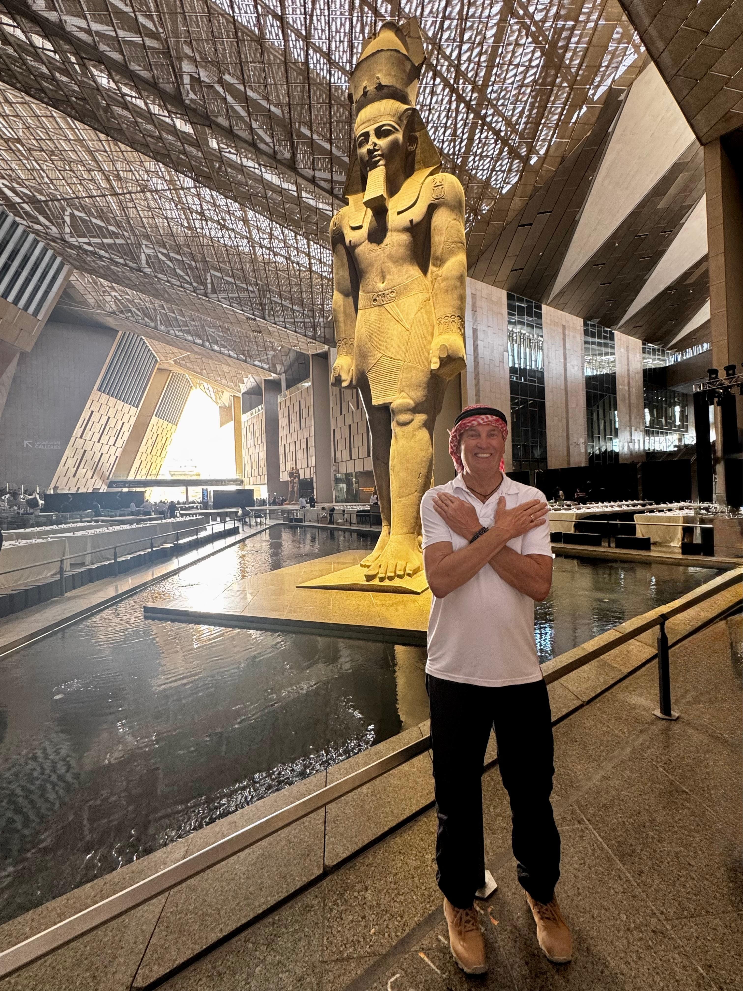 Visitors inside the Grand Egyptian Museum, viewing the colossal Ramses II statue and ancient archaeological collections during a guided muse