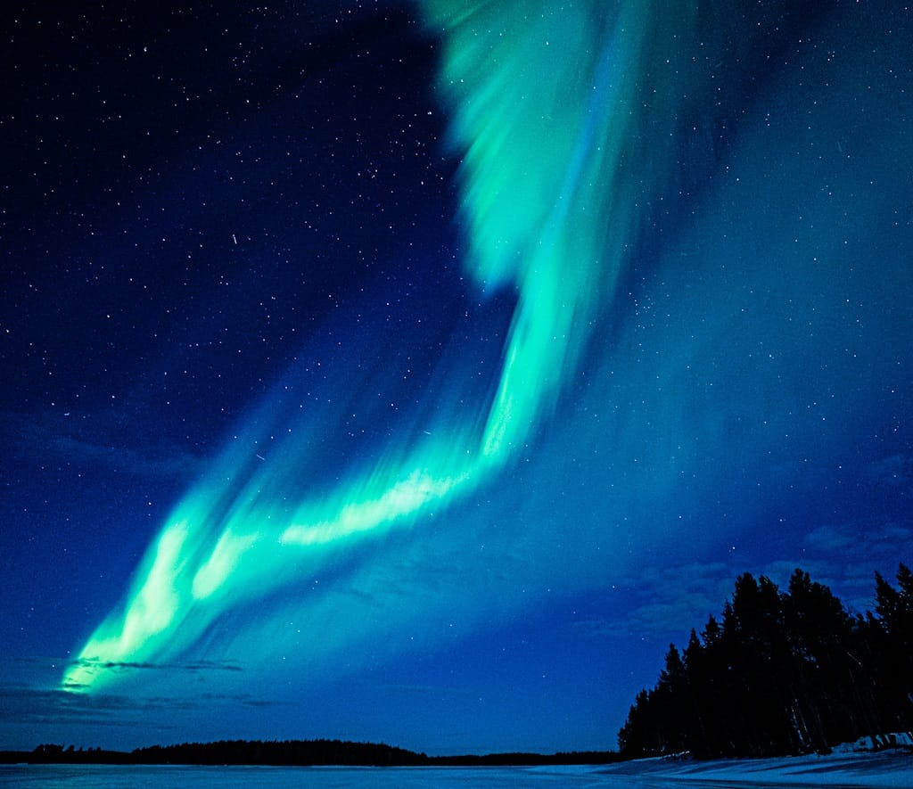 Bright green Northern Lights glowing over Lapland´s night sky