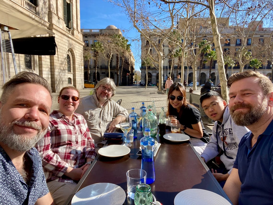 Guests and tour guide are sitting around a table outside on a terrace of a restaurant