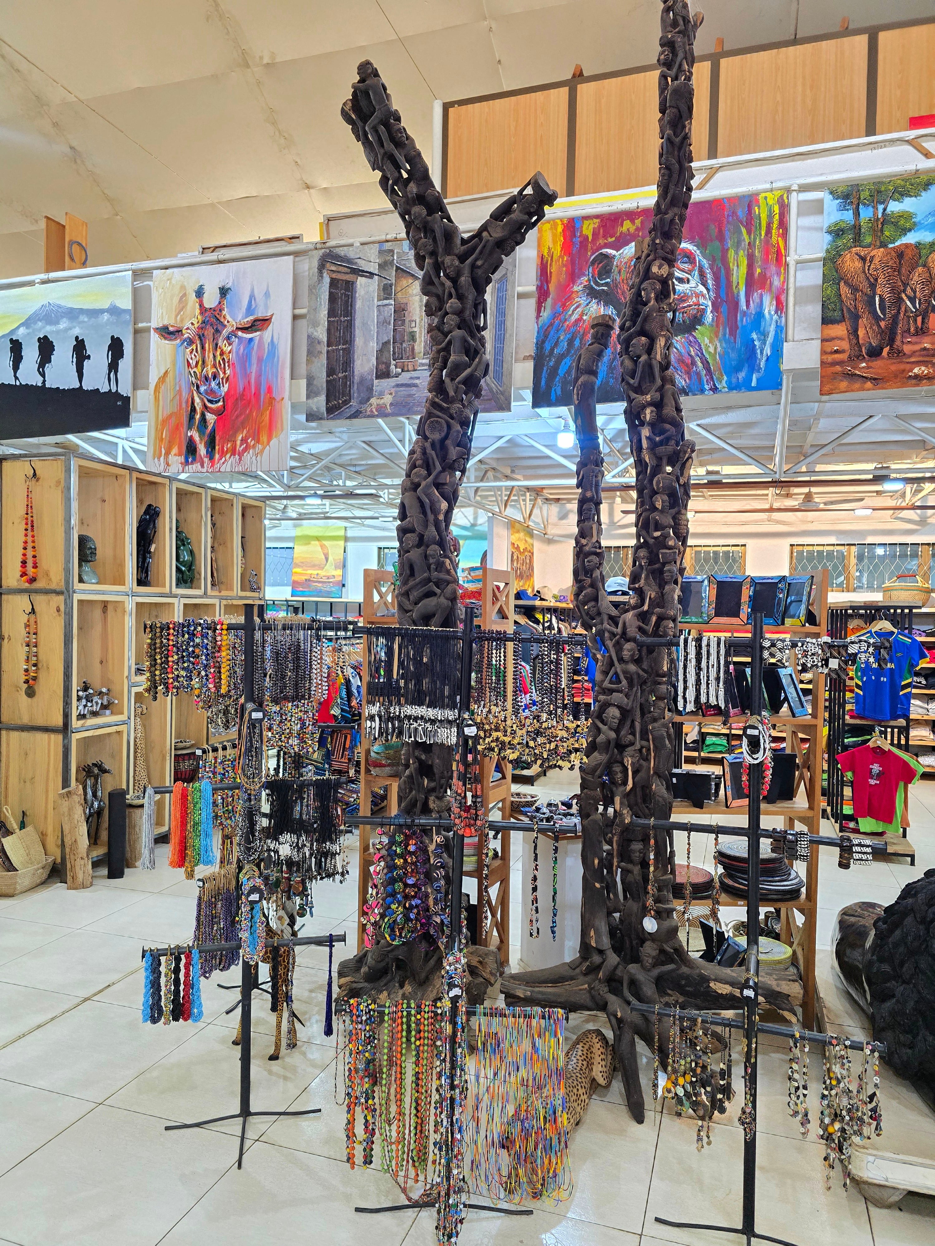 A spacious souvenir shop interior displaying colorful African paintings, handcrafted wooden art, and local gift items.