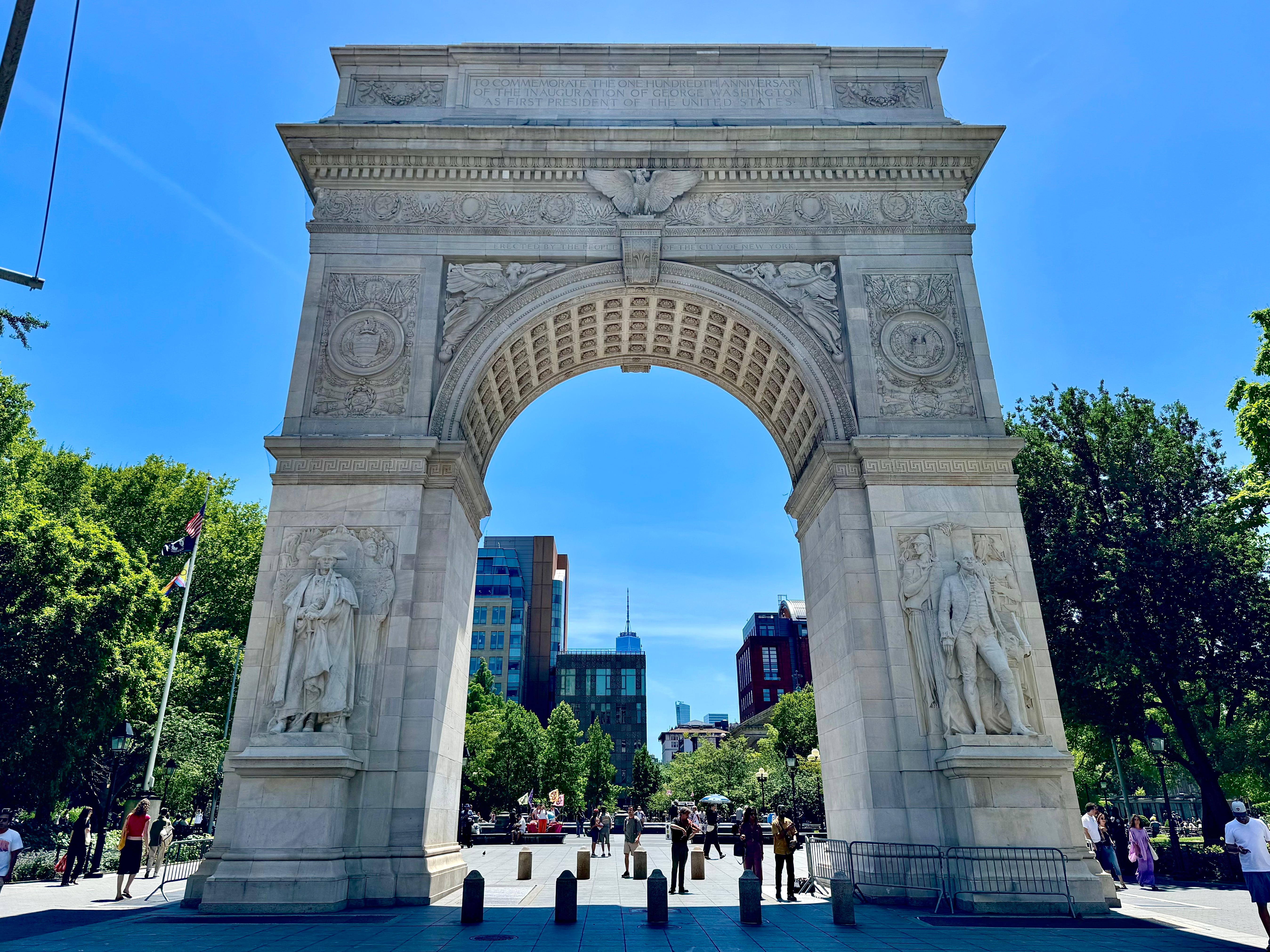 The Washington Square Arch with trees and the park stretching beyond it.