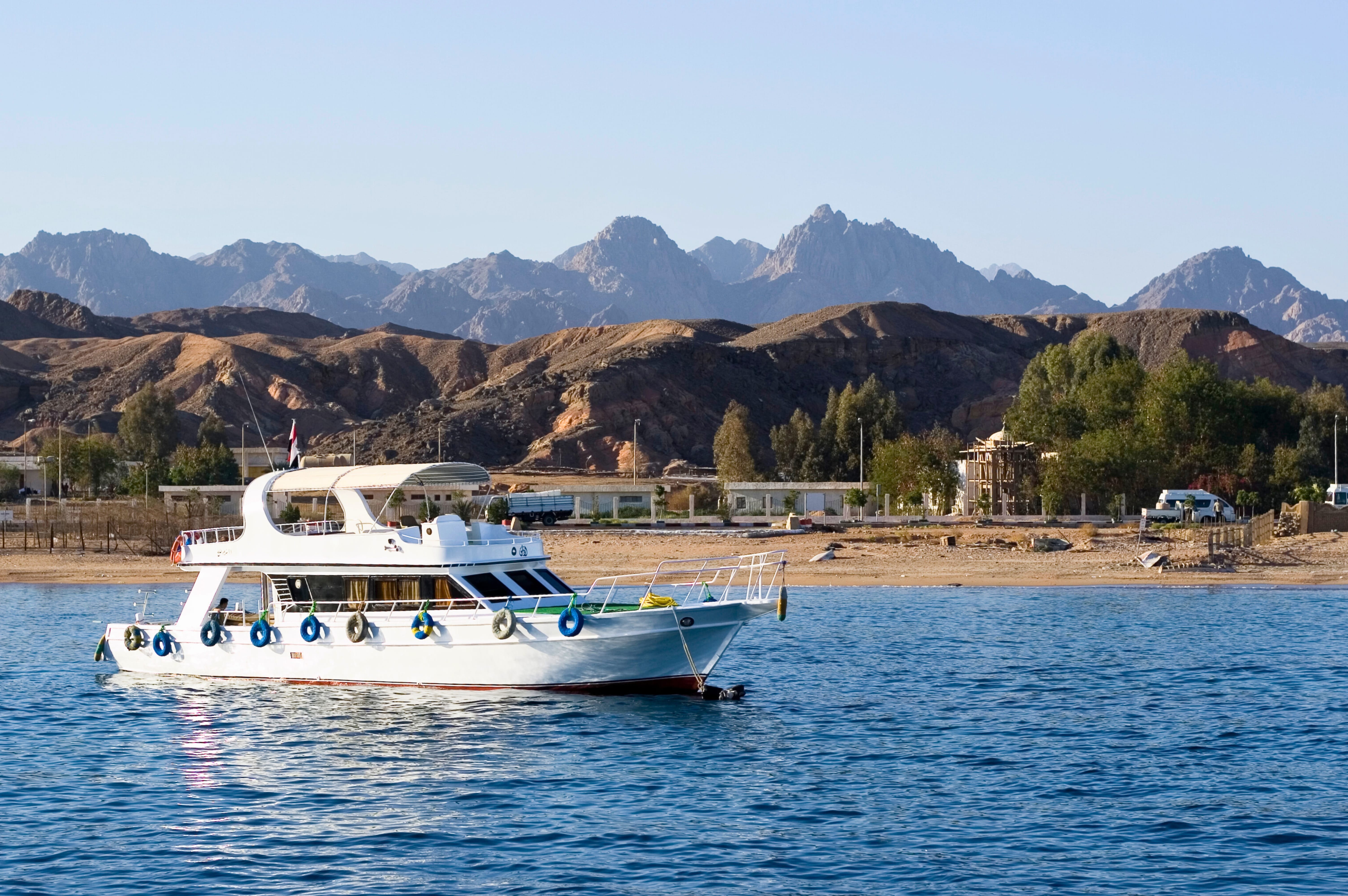 A white luxury yacht floating on the Red Sea with the rugged Mountains in the background when heading towards Tiran Island..