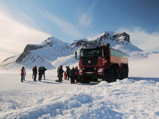 Red Monster truck on glacier with guests enjoying the view