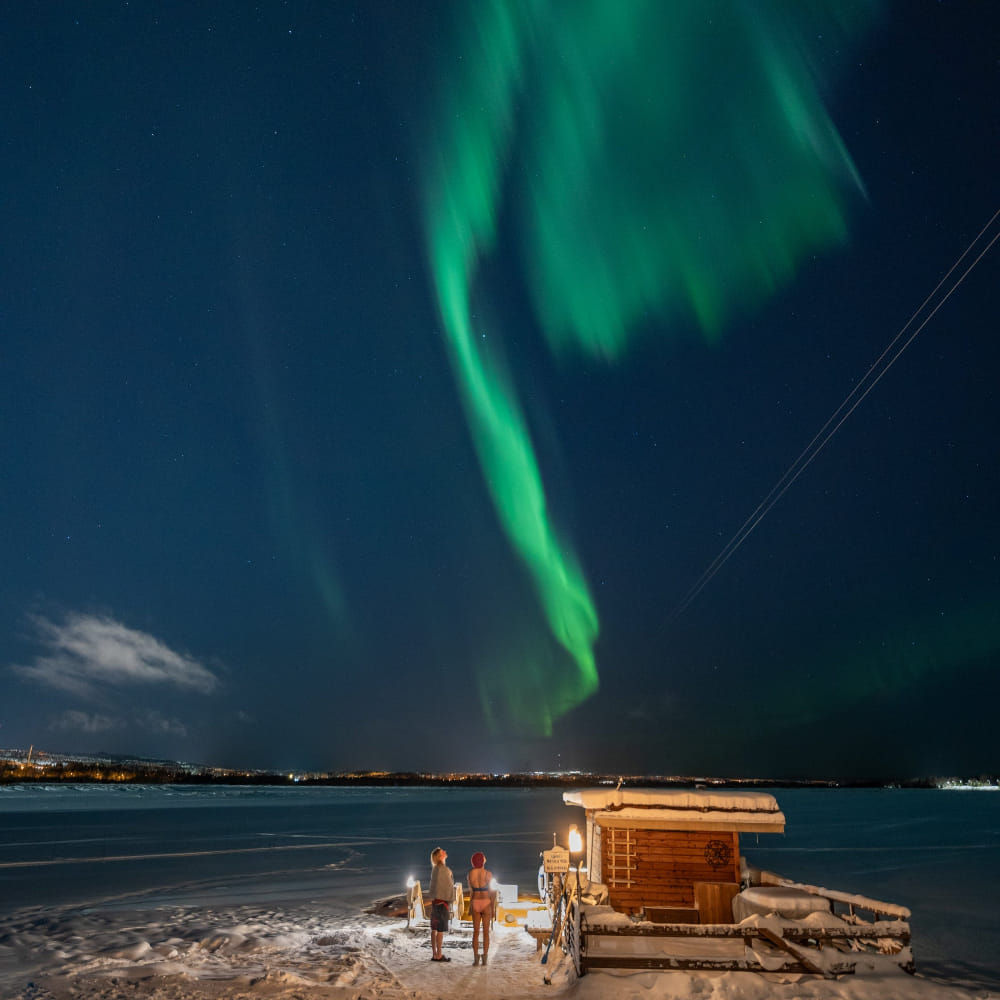 People watching northern lights after ice swimming at Roiske Arctic Sauna Retreat