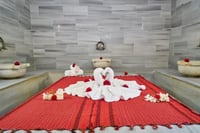 hammam marble table decorated with red fabric, rose petals, and towel art