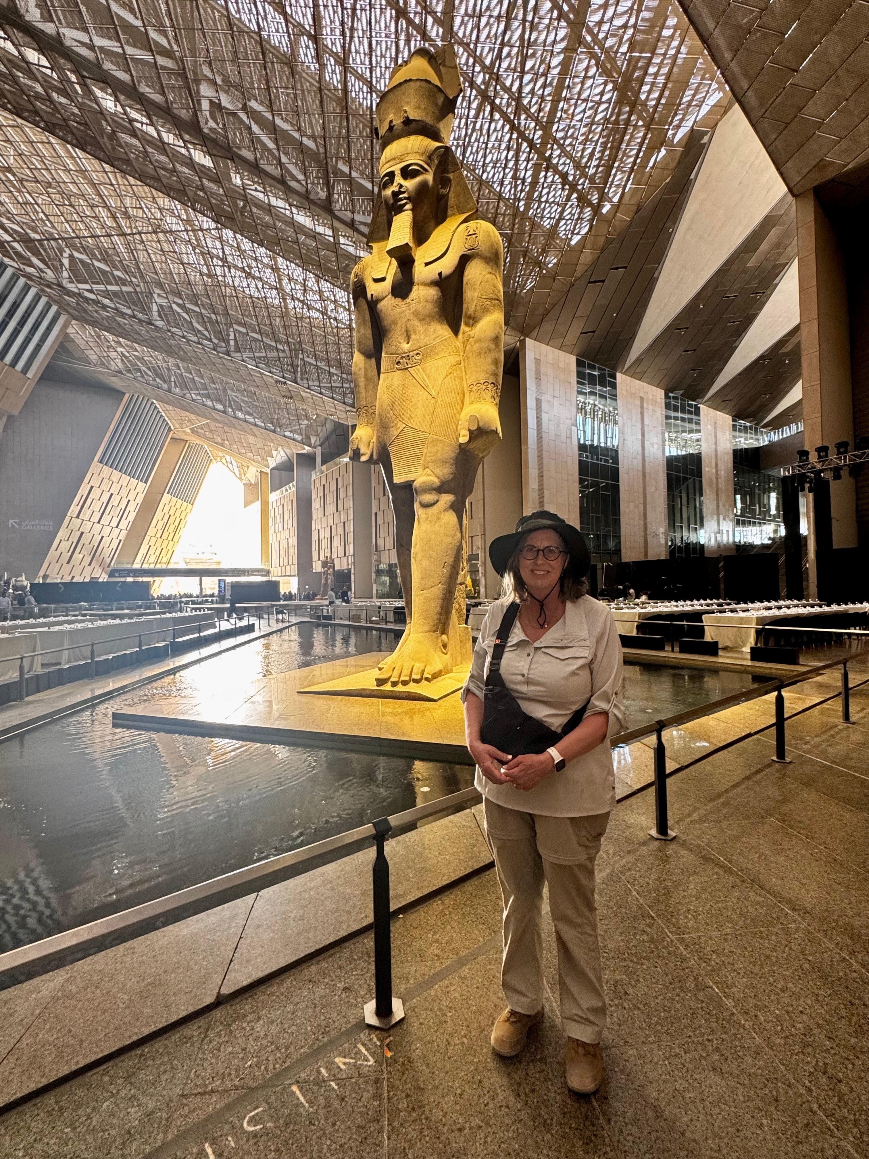 Visitors inside the Grand Egyptian Museum, viewing the colossal Ramses II statue and ancient pharaonic artifacts during a guided museum tour