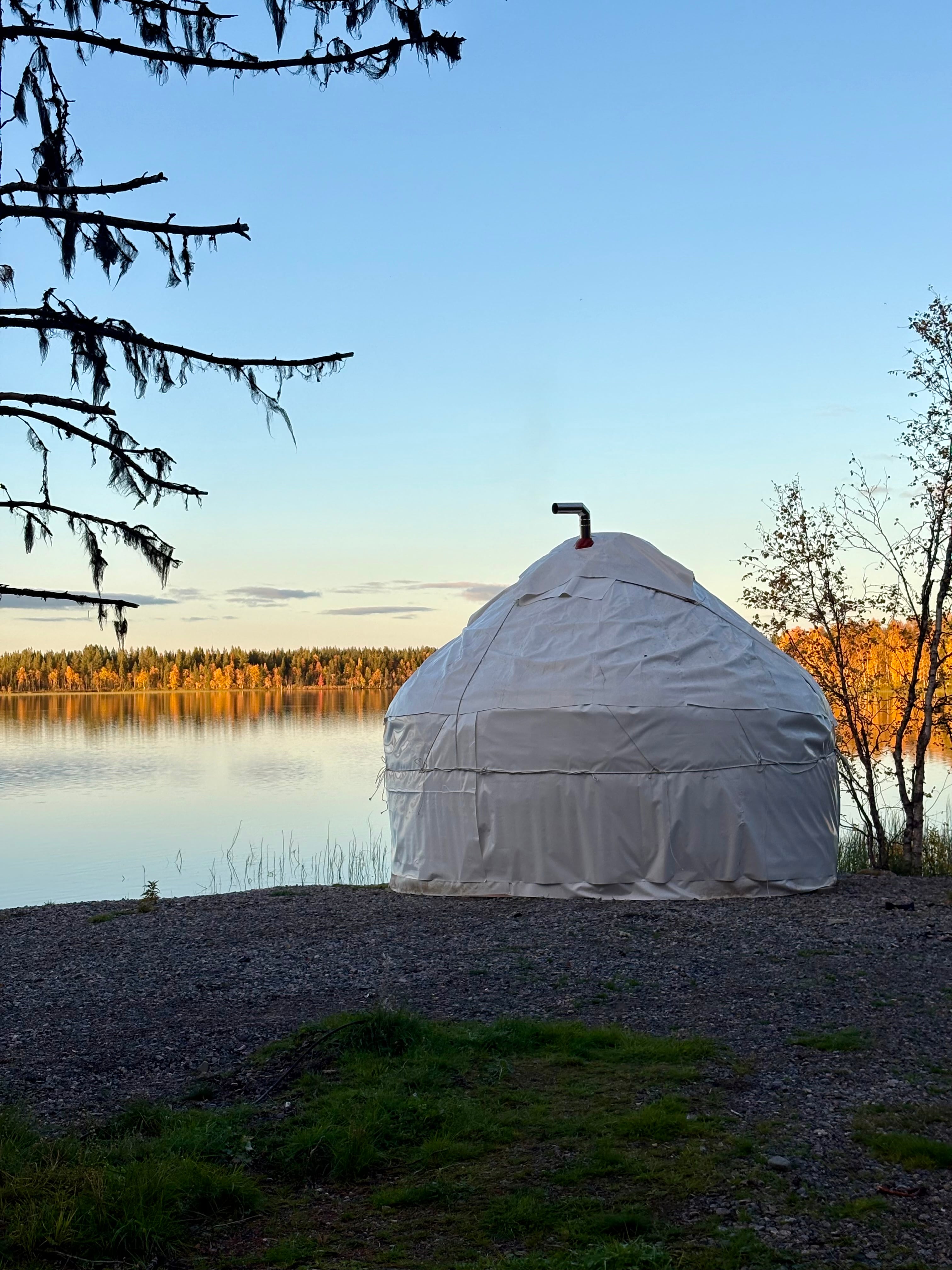 White handcrafted yurt sauna beside Rautusjärvi lake in Finnish Lapland.