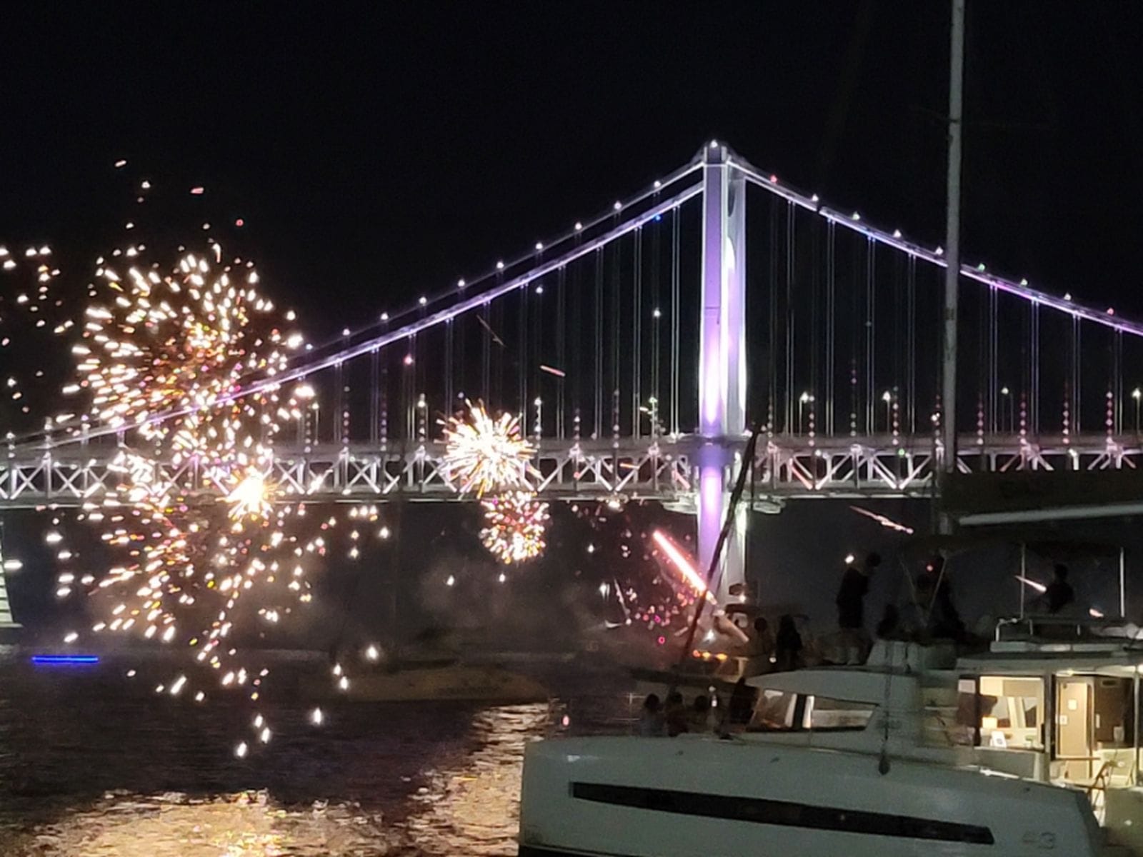 Fireworks exploding over the ocean near Gwangandaegyo Bridge during a yacht ride.