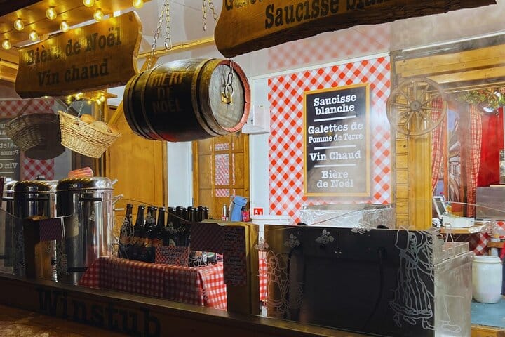 A mulled wine chalet (vin chaud, Christmas beer) with hanging barrels, menus, and products for sale in Place Saint-Thomas.
