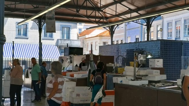 Inside of Aveiro Fish Market with seafood stalls, fish boxes, workers, and visitors