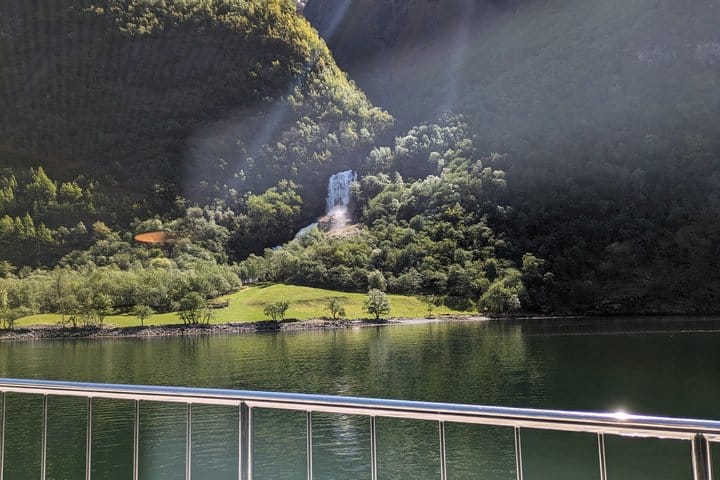 Waterfall across calm fjord waters viewed from the cruise ship