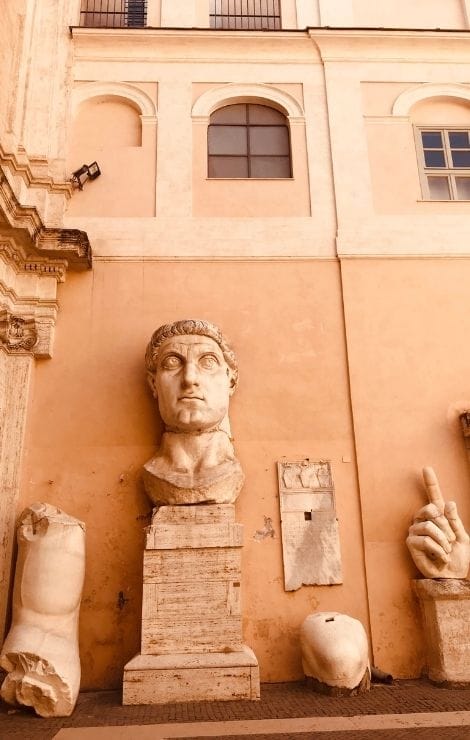 Fragment of a giant marble statue: Emperor Constantine’s head displayed on an ochre courtyard wall at the Capitoline Museums.