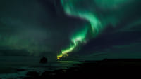Northern Lights visible above Reykjavík’s coastline during a boat tour