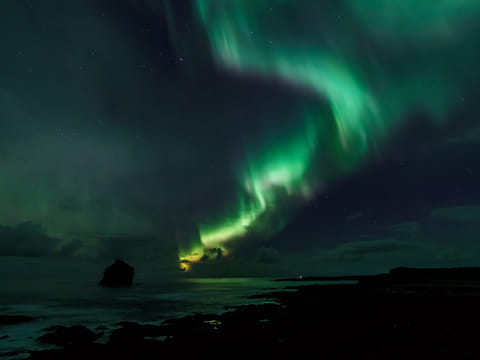 Northern Lights visible above Reykjavík’s coastline during a boat tour