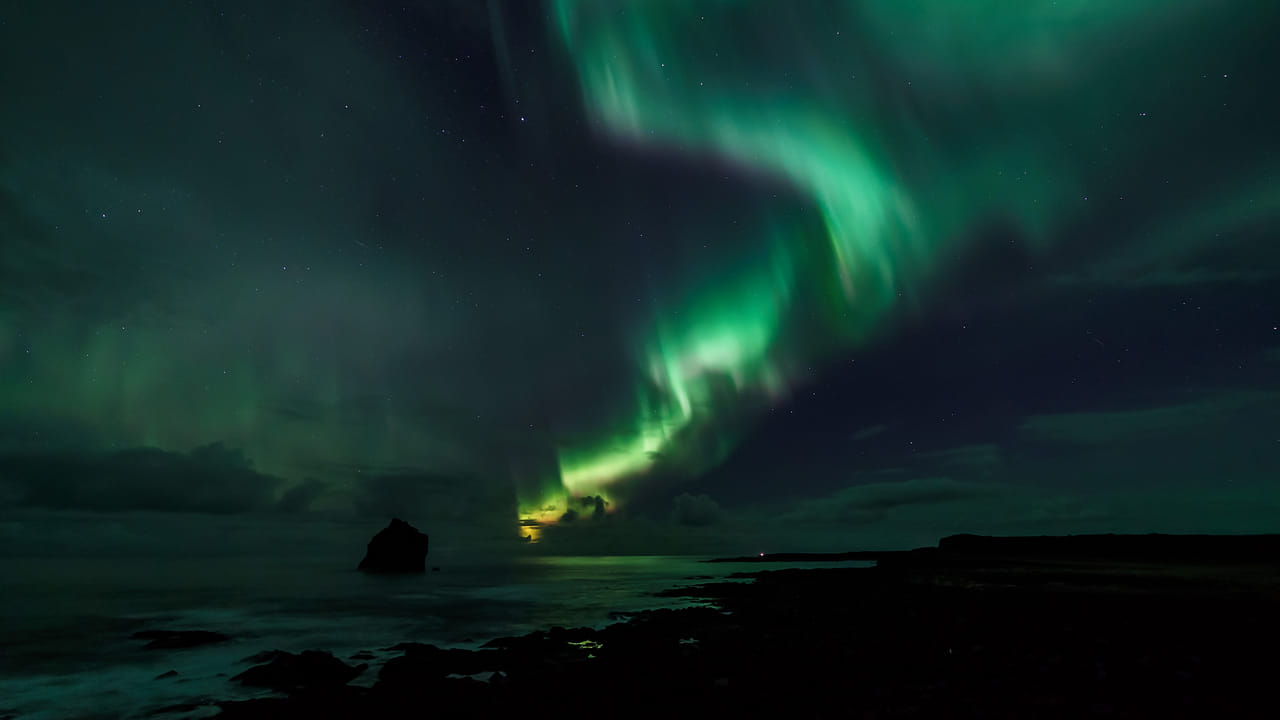 Northern Lights visible above Reykjavík’s coastline during a boat tour