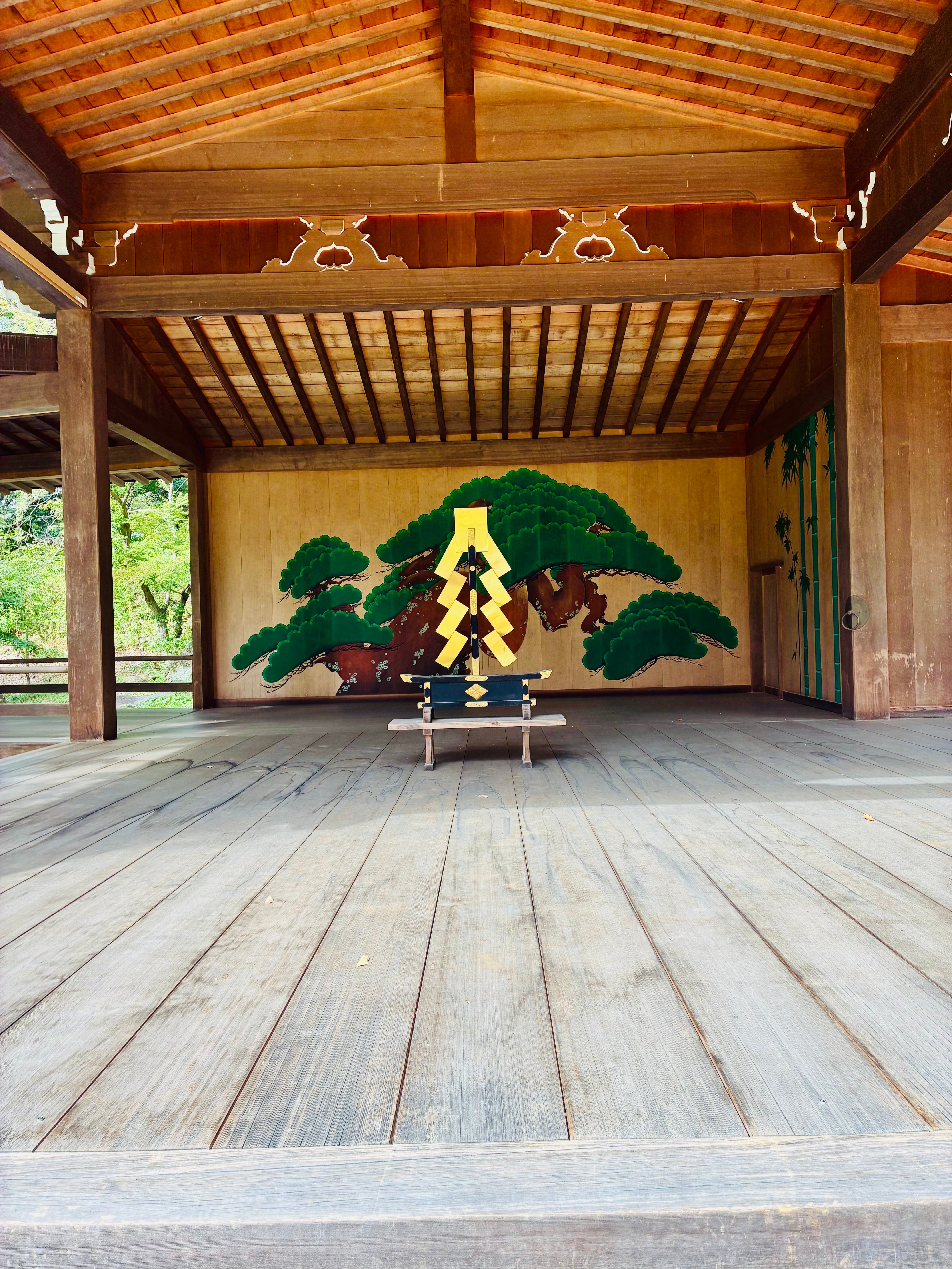 A traditional wooden Noh theater stage at Takeda Shrine with painted pine trees in the background.
