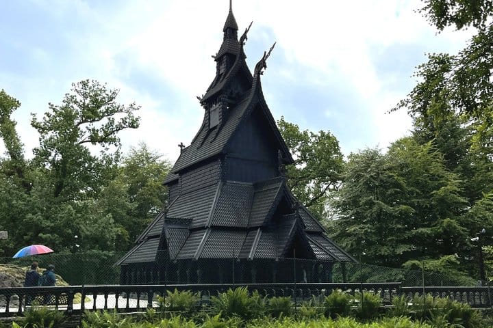 Fantoft Stave Church surrounded by green trees on an overcast day