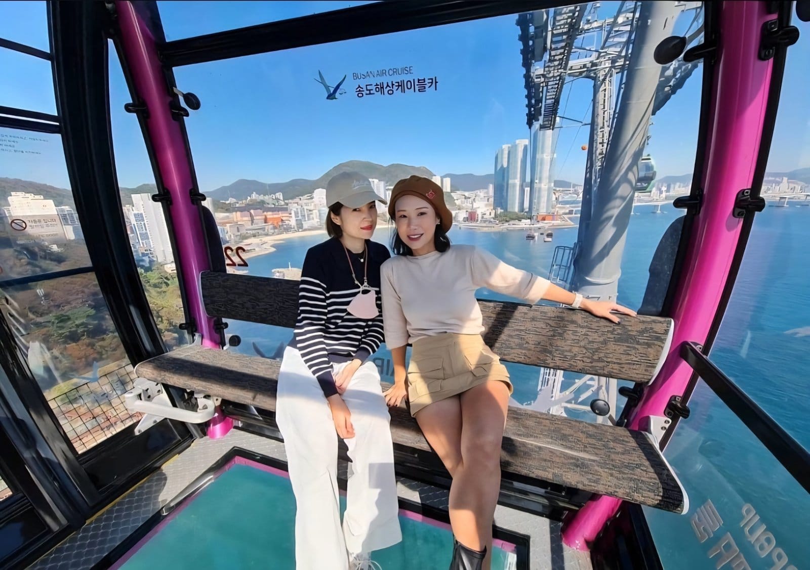 Two people sitting inside the Songdo Marine Cable Car overlooking the sea.