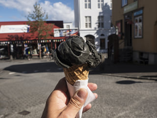 A picture of a ice cream cone with a black coloured scoop of liquorice flavoured Ice Cream.