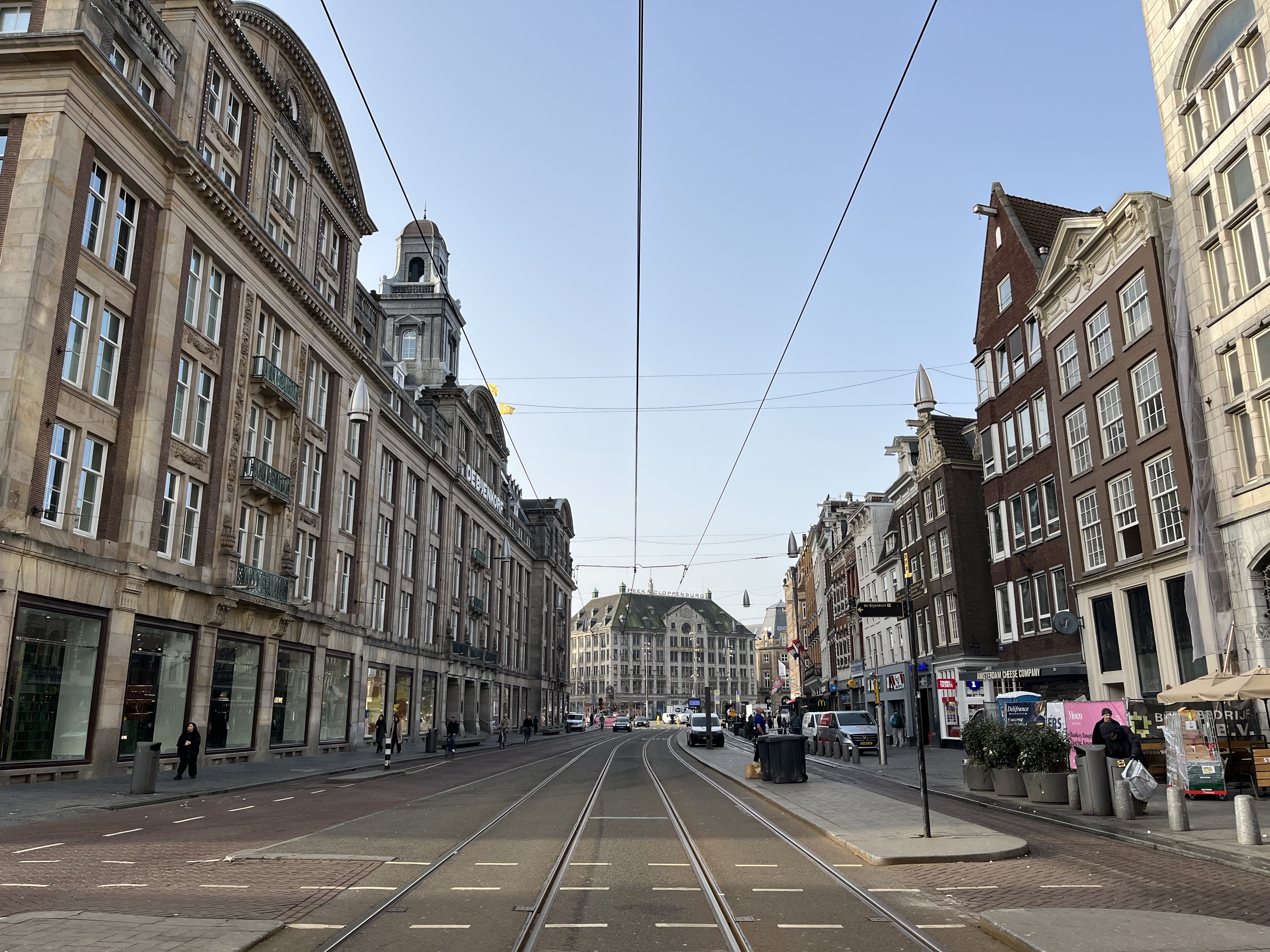 Damrak street in Amsterdam city center with tram tracks during a private hop-on hop-off tour