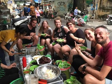A group of friends is happily enjoying food in Hanoi.