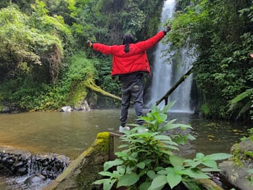 ​A traveler enjoying the refreshing view of Marangu Waterfalls in Kilimanjaro.