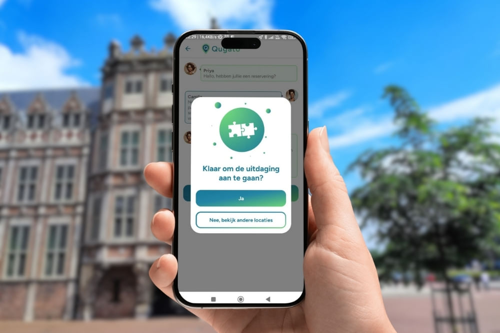Phone showing the app interface of the Arnhem City Detective game in front of the Duivelshuis van Maarten van Rossum.