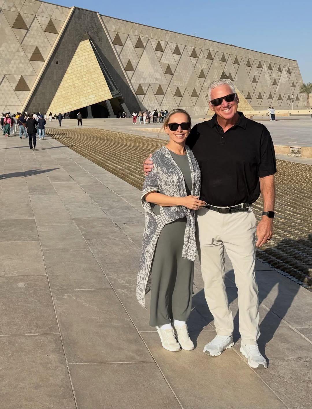 Visitors walking through the Grand Egyptian Museum galleries, viewing ancient statues and collections.