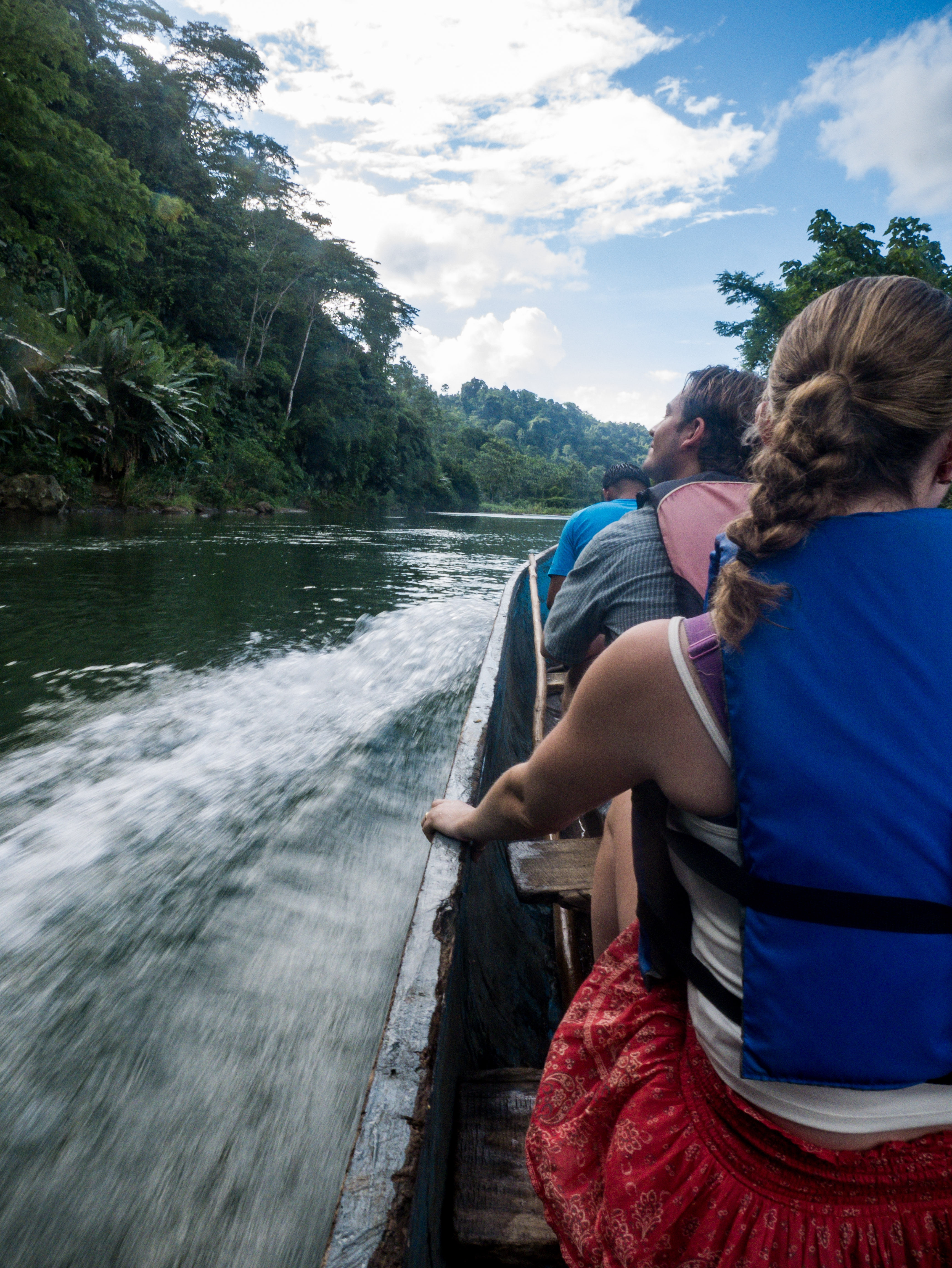Tourists traveling by dugout canoe on the Yorkín River surrounded by tropical rainforest on a Bribri cultural tour in Costa Rica.