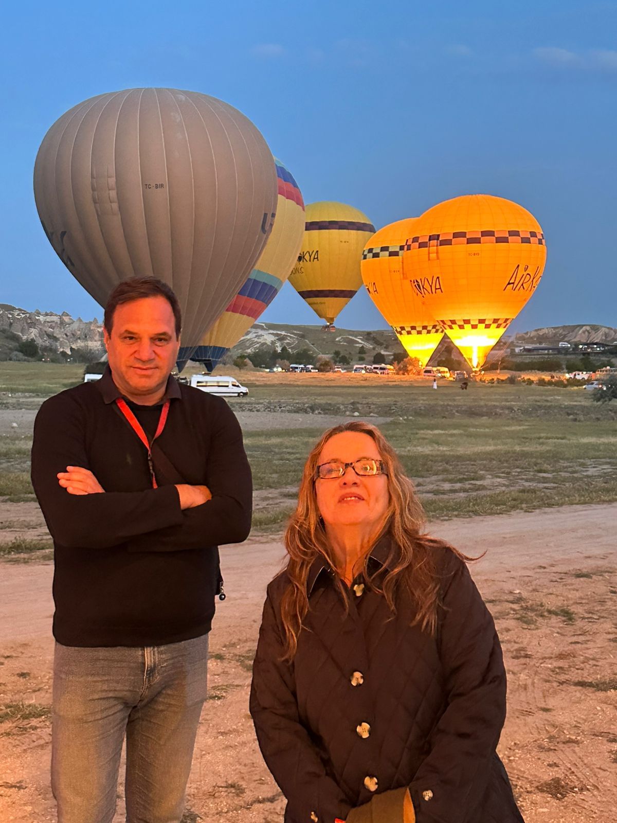“Tour guide coordinating the setup of hot air balloons at sunrise, preparing for an early morning flight for guests.”