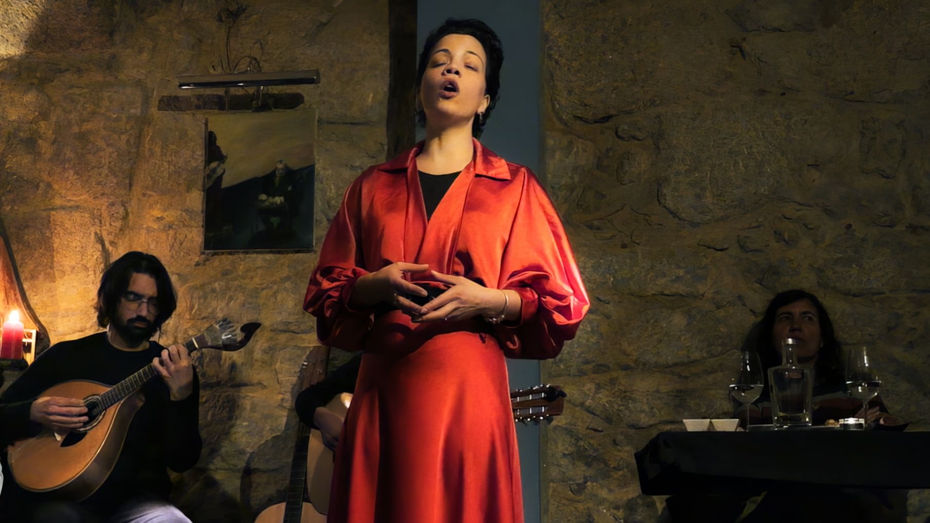Image of a female Fado singer performing with emotion, accompanied by musicians, part of Cooltour Oporto's Fado Dinner Show with Night Tour