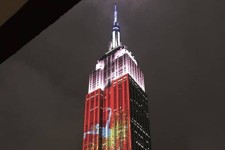 Empire State Building illuminated at night with red and gold lighting