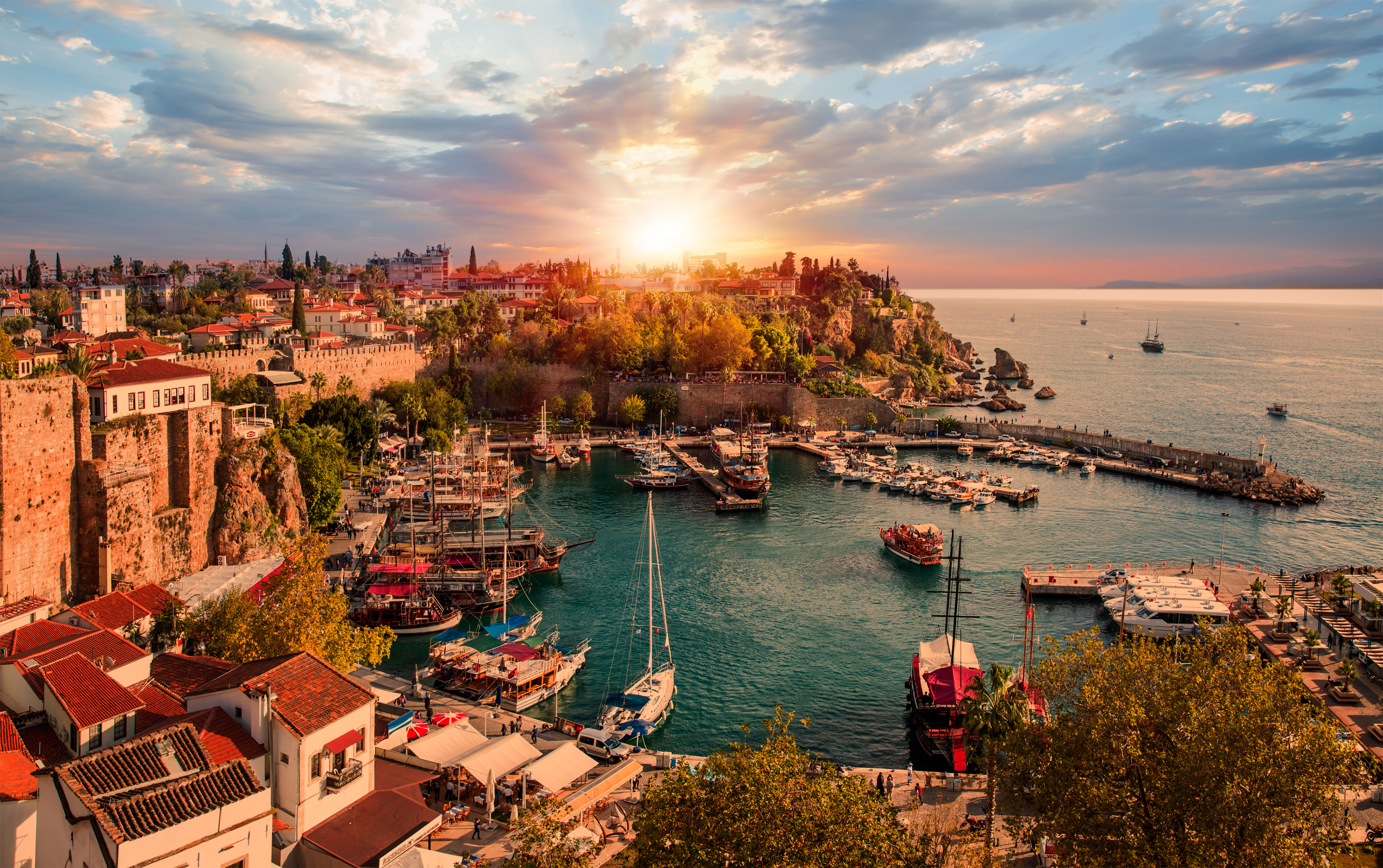 “Narrow cobblestone streets and traditional Ottoman-style buildings in Antalya’s historic Old Town, Kaleiçi, bustling with people.”