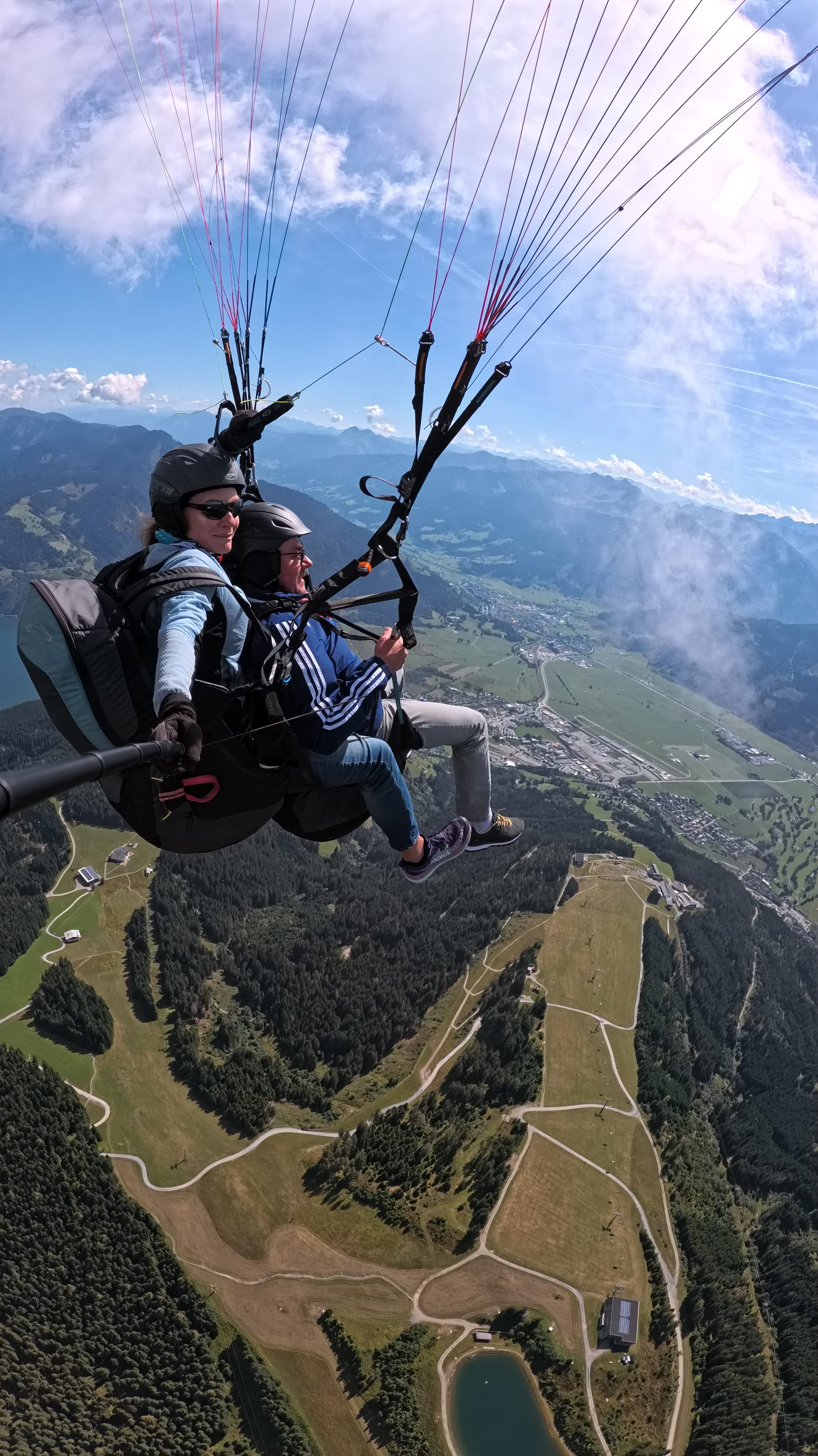 A man paragliding with a female tandem pilot over the Schmittenhöhe, enjoying a birthday tandem flight