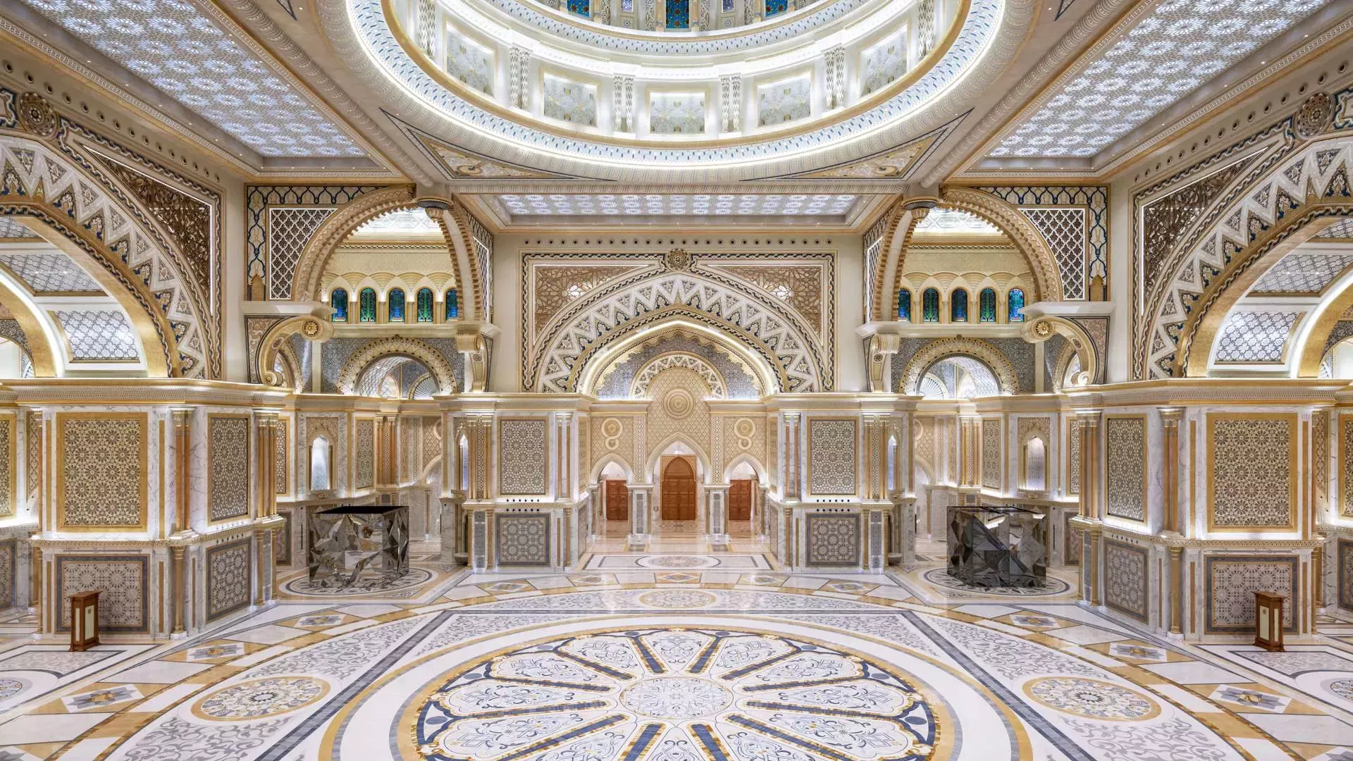 A grand, ornately decorated hall features intricate white and gold archways, a central patterned floor, and a towering dome at Qasr Al Watan, Royal Palace.