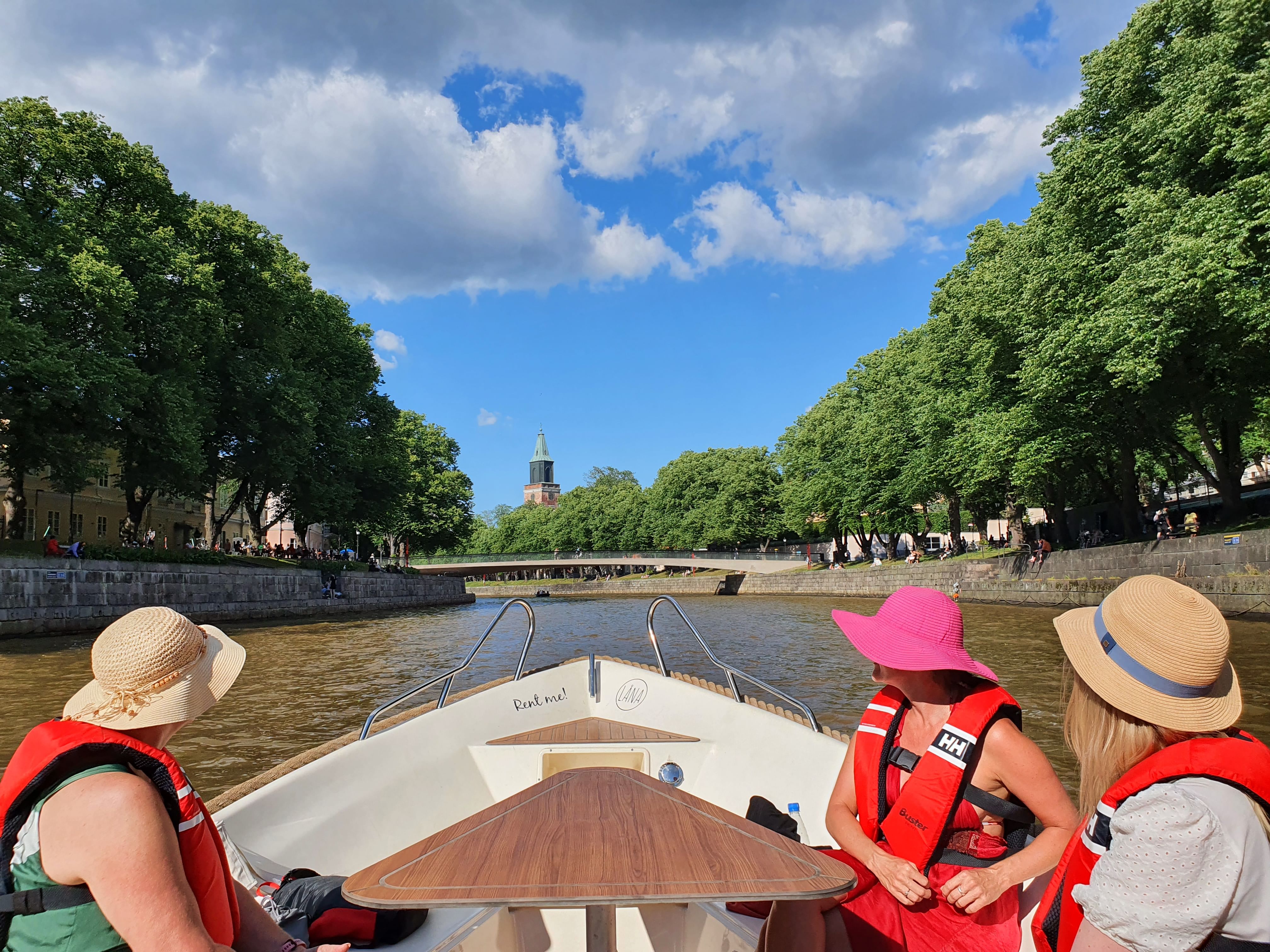 People on a boat moving on the river, Turku Cathedral on the background