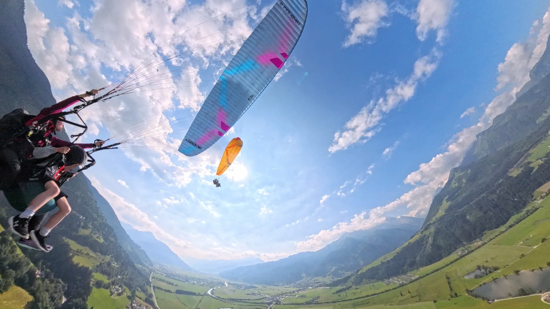 Two paragliders flying above Kaprun in Austria scenig tandem couple flight with male and female pilot