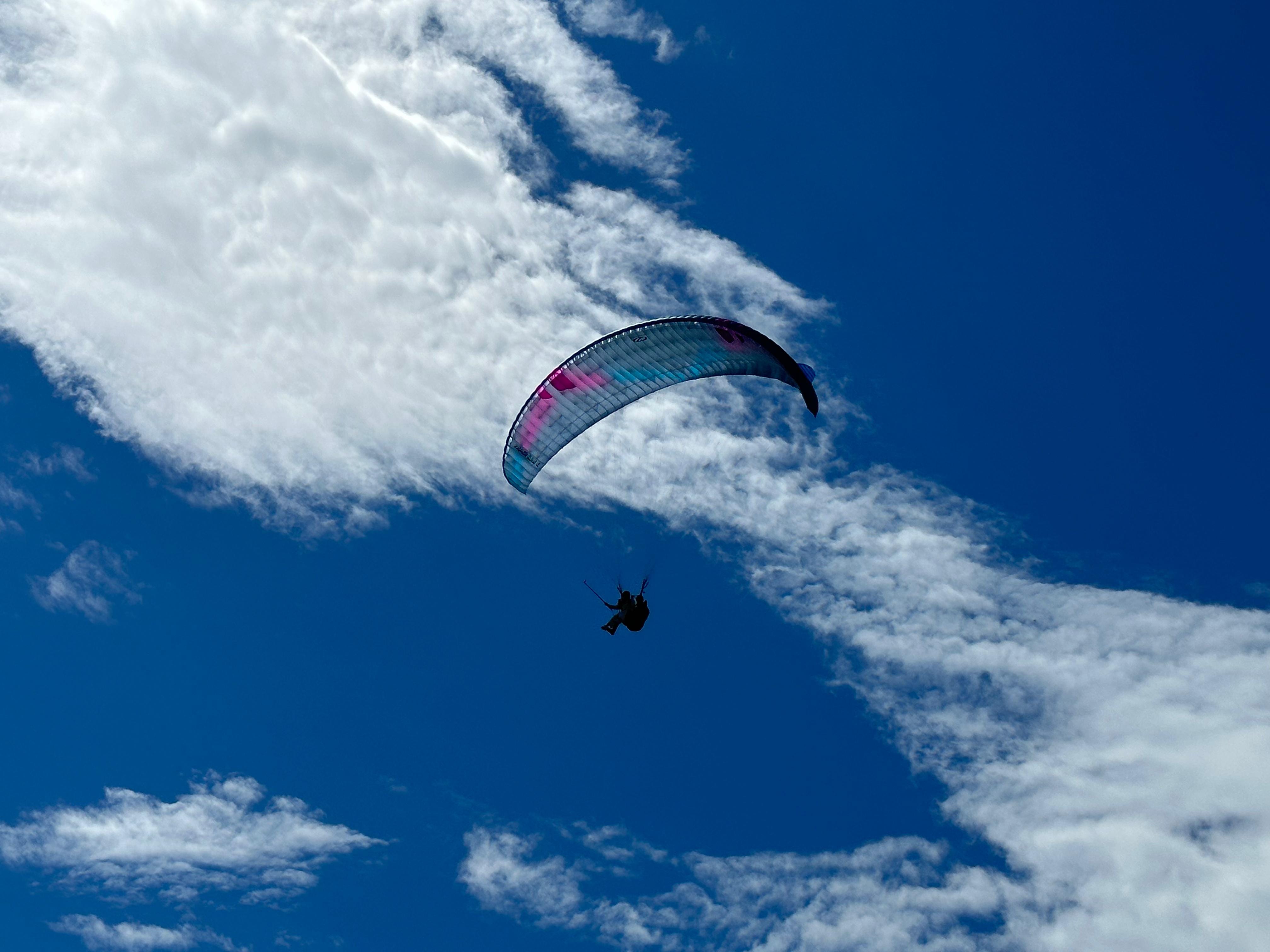 paraglider over the blue sky with vivid clouds, female tandem paragliding pilot