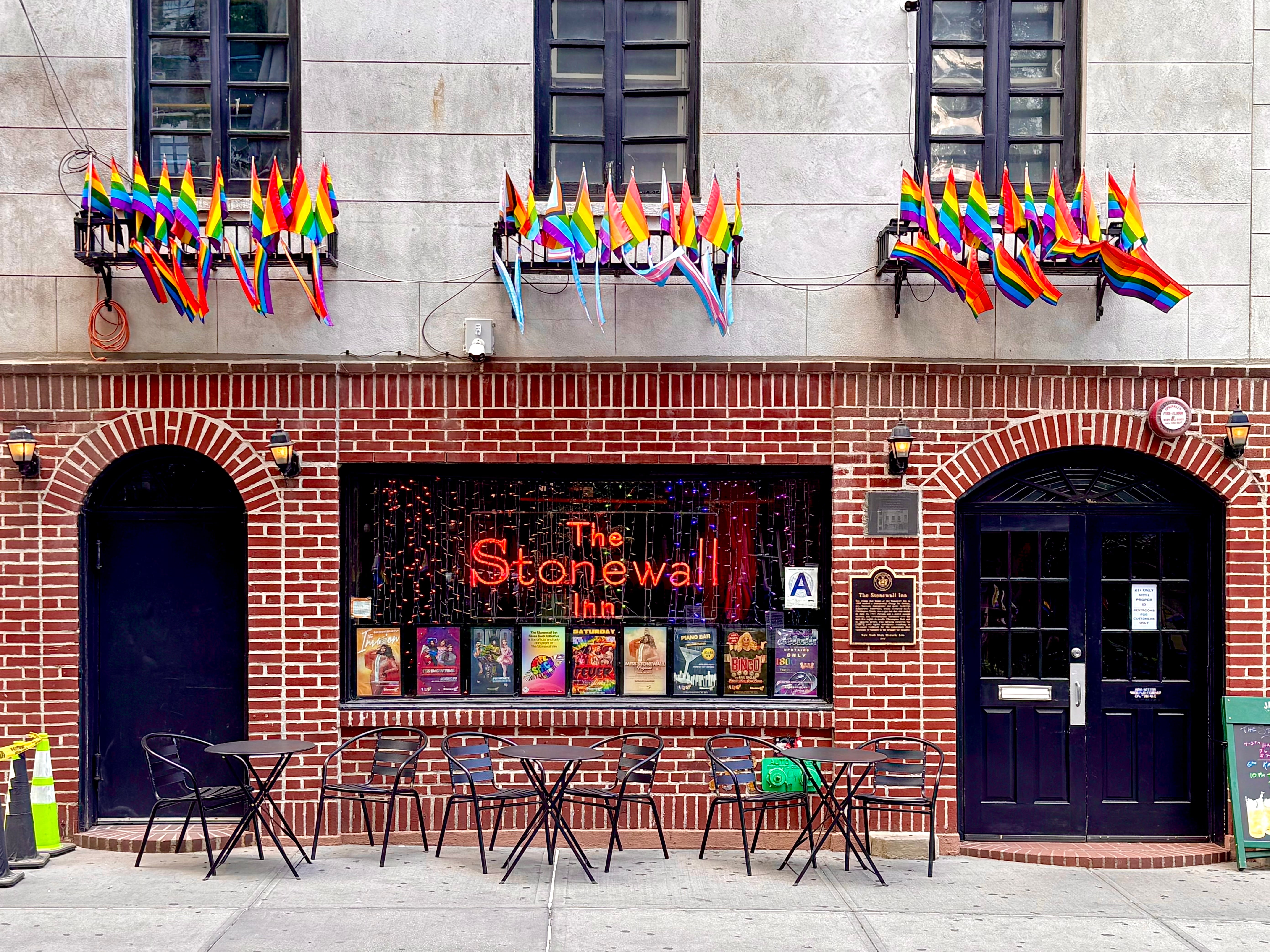 The Stonewall Inn storefront decorated with rainbow flags and Pride banners.