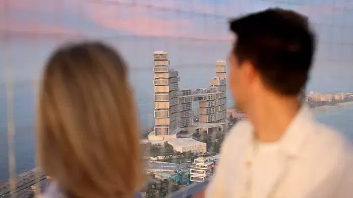 A man and woman with their backs to the camera look out at a tall modern building from behind a wire mesh at The Dubai Balloon at Atlantis.